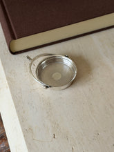 Angled view of the spur catchall, the projecting stem and curved hoop framing the guilloche interior and polished rim