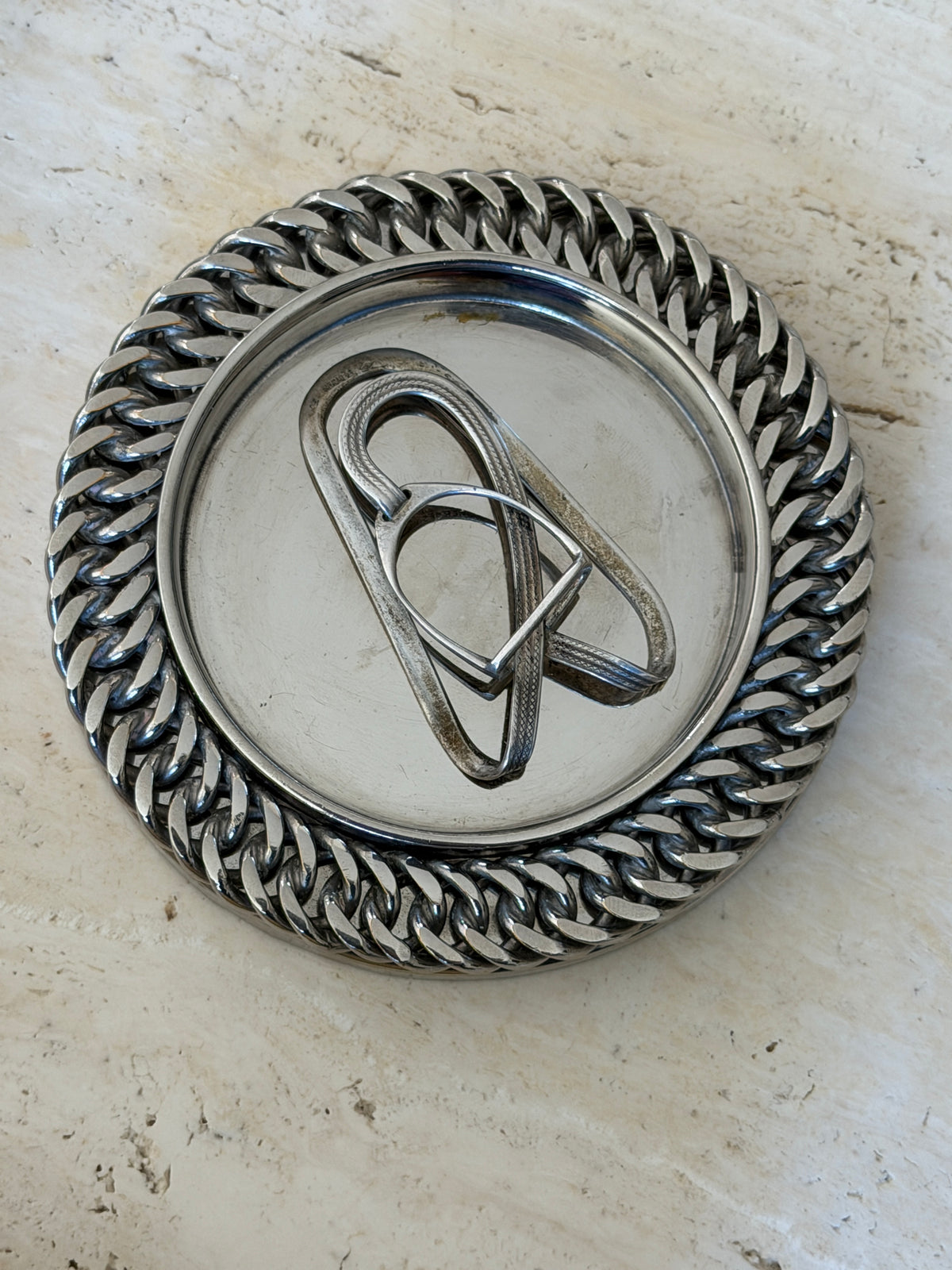 Hermes equestrian money clip centered in a silver dish ringed with heavy curb chain
