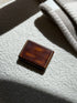 Keller Paris lacquer box on a cream boucle surface in raking sunlight, light surface wear visible on the polished lid