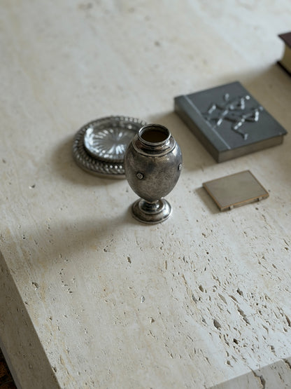 High angle view of the Buccellati vase beside a silver chain coaster with glass insert and a pewter box with runners in relief