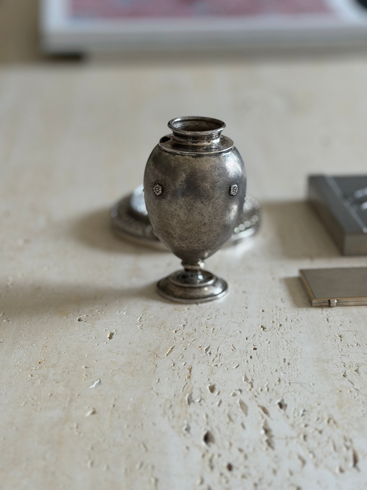 Front view of the egg shaped silver vase showing two applied floral rosettes on the hand engraved surface