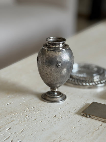 Mario Buccellati vase with rosettes and a stepped round foot on travertine, a silver cigarette case and chain coaster beside
