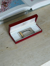 Must de Cartier fluted cigar cutter resting in its open red case, the satin lid printed must de Cartier, with gold bands at one end