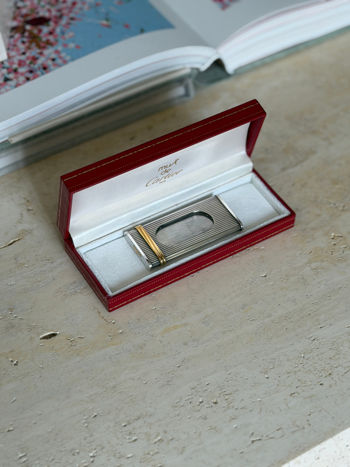 Must de Cartier fluted cigar cutter resting in its open red case, the satin lid printed must de Cartier, with gold bands at one end