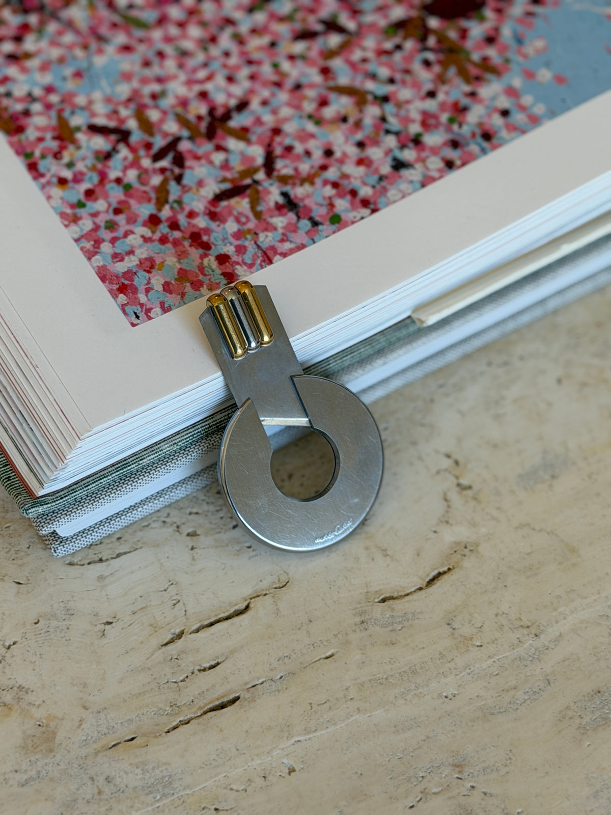Must de Cartier cigar cutter opened with its sliding blade extended, clipped over the edge of a book page