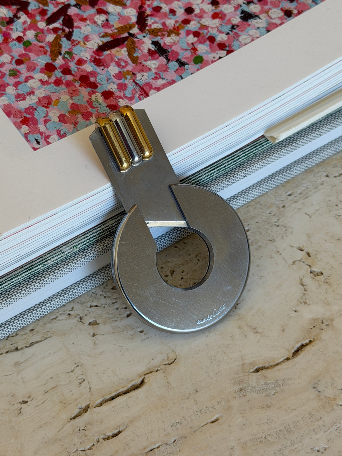 Close view of the opened Cartier cutter, the blade arm and ribbed tricolor bars with the must de Cartier signature on the brushed steel