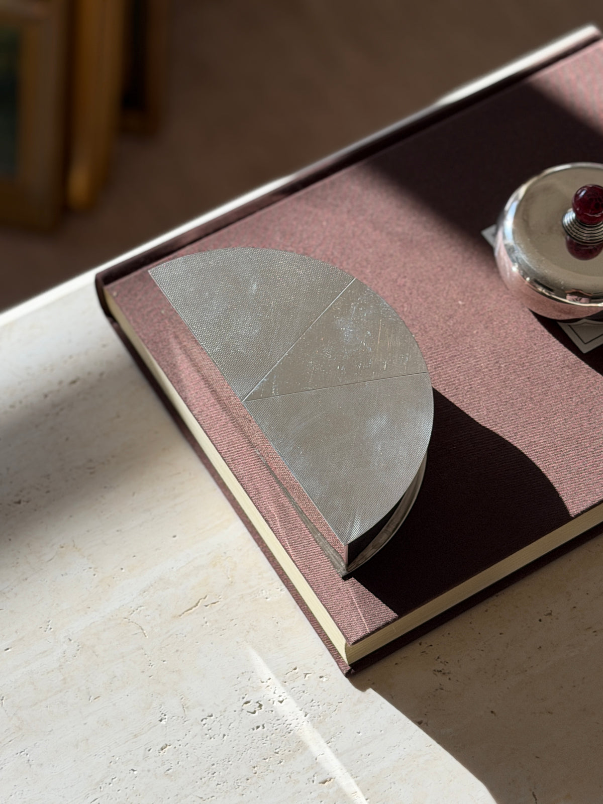 Overhead view of the Olivetti demilune box on a rose brown book, fine diagonal guilloche lines running across each sector of the lid