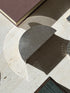 Top down view of the half round engine turned box on travertine, its reflected light arcing across the stone beside a chain link coaster