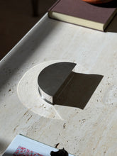 Olivetti modernist box on a travertine table casting a crisp shadow, the stepped polished base visible below the textured lid