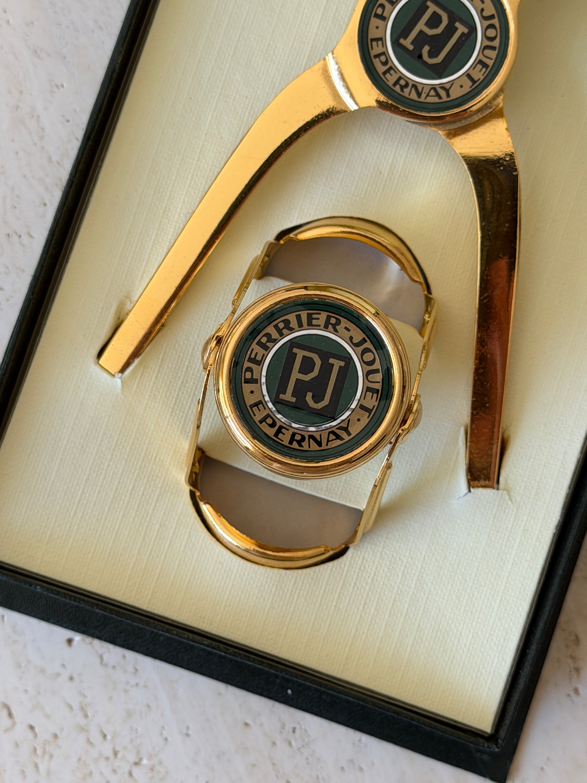 Close-up view of gold champagne stopper and opener with green PJ medallion emblem available at Collectors Gene