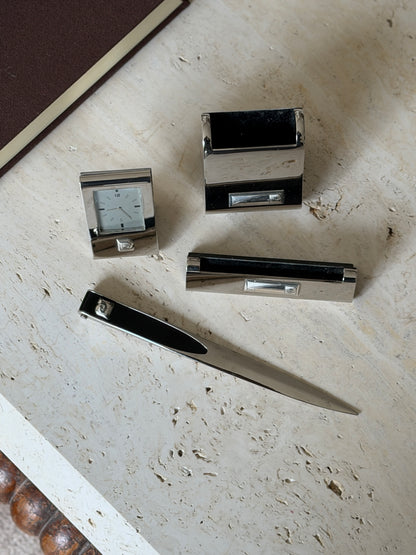 Overhead view of the four piece Pierre Cardin set, mirror chrome pieces with black lined interiors and a tapered letter opener
