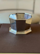 Eye level view of the octagonal bowl showing its faceted sides, molded rim, and stepped octagonal foot on a brown book