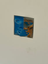Rene Berthet bronze relief of two overlapping faces, one in textured cobalt blue patina and one in burnished copper bronze, set into a white shadowbox window