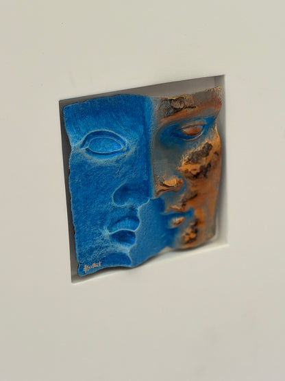 Close angled detail of the patinated bronze relief, the torn edges, raised eyelids, and mottled copper patina casting shadow into the recess