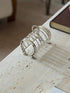 Angled view of the horseshoe toast rack from the far end, the arched dividers casting striped shadows on travertine