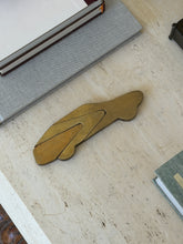 Side profile view of solid bronze stylized car paperweight desk object on marble surface