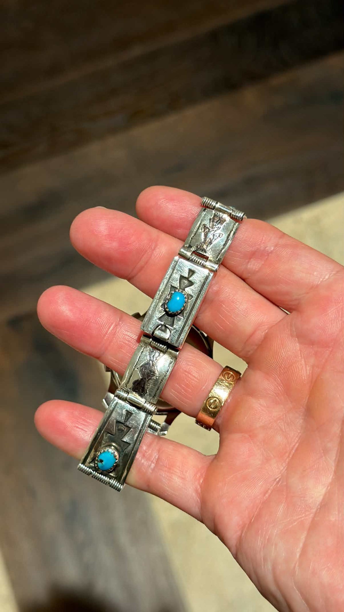 Close-up view of vintage sterling silver link bracelet with Aztec motif stampings and turquoise cabochons from Collectors Gene