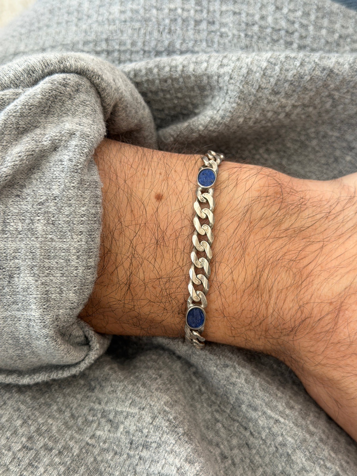 Vintage German sterling silver curb link bracelet with oval lapis lazuli stones, worn on the wrist against a gray knit sleeve