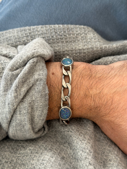 Vintage German sterling bracelet of open curb links set with blue opal cabochons, worn on the wrist over a gray knit sweater