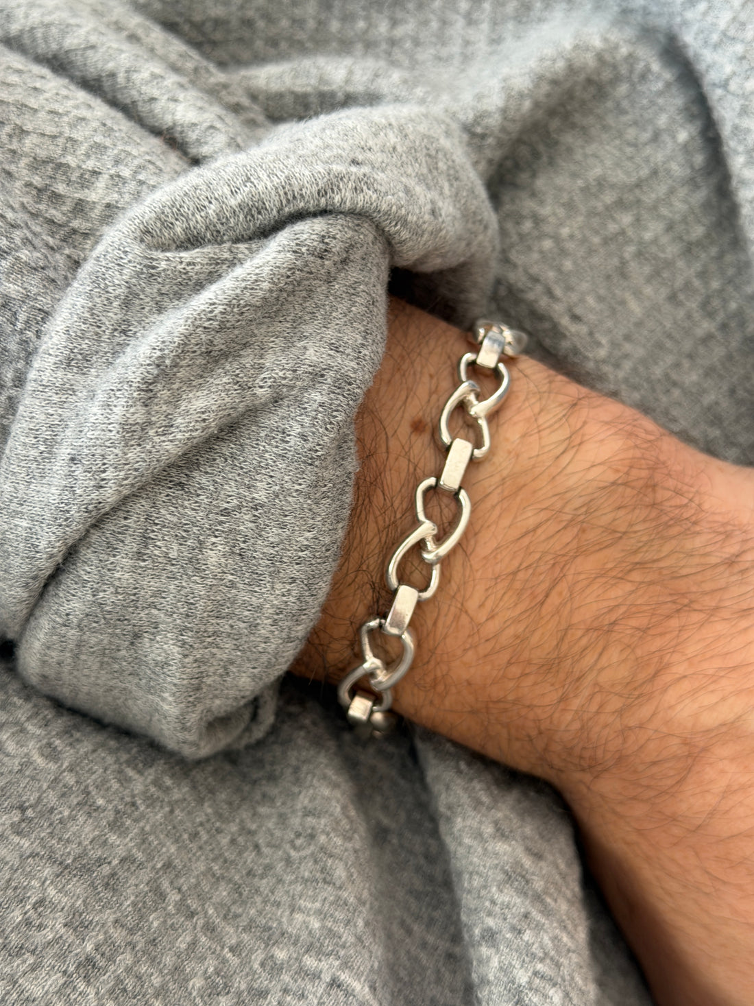 Angled wrist view of the sterling oval link bracelet, polished interlocking loops joined by smooth rectangular bars