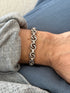 Mid century German sterling silver bracelet of interlocking double rings and grooved bar links, worn on the wrist against blue denim