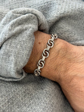 Angled wrist view of the ring link bracelet, pairs of polished silver rings joined by ribbed connectors over a gray sweater