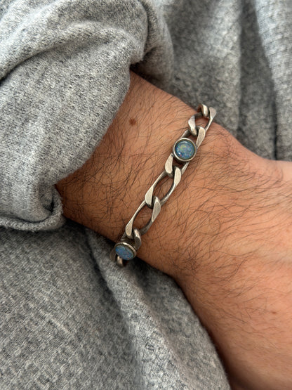 Angled wrist view of the opal link bracelet, a blue opal with flashes of green and violet fire in a round silver bezel