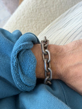 Bracelet worn on the wrist near a cream ribbed top and blue sweatshirt cuff