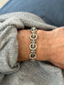 Vintage Mexican sterling silver bracelet of round rings joined by bundled parallel bars with studded ends, worn on the wrist over a gray sweater and blue denim