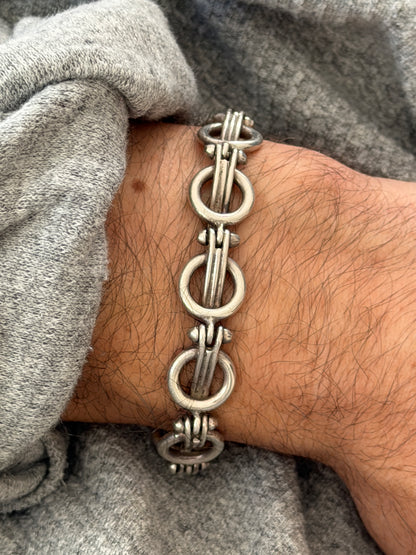 Close wrist view of the ring and bar link bracelet, the satin silver rings and ribbed bar bundles with small rivet like studs