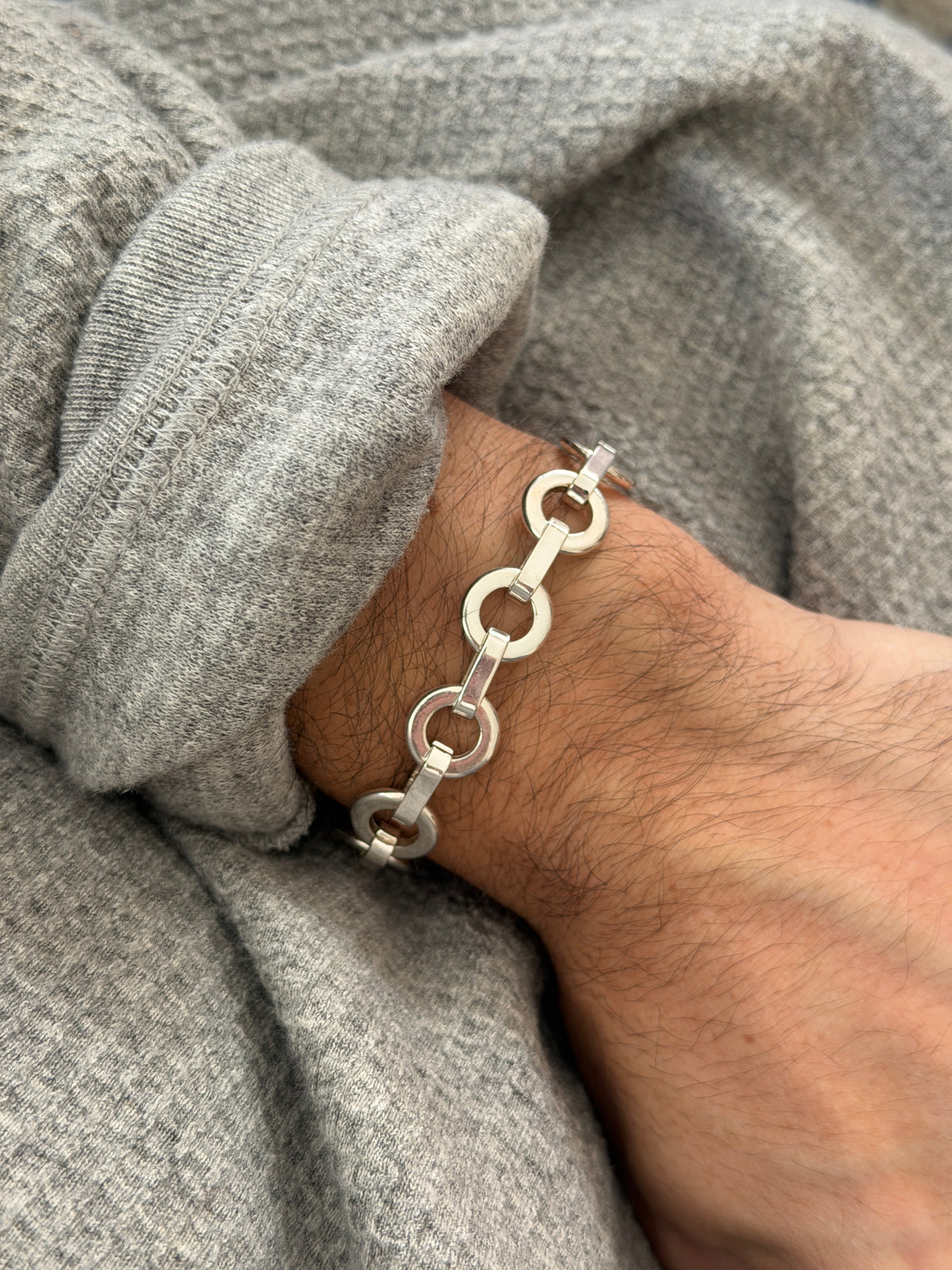Angled wrist view of the round link bracelet, bright washer shaped rings alternating with smooth rectangular bars
