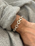 Angled wrist view of the round link bracelet, bright washer shaped rings alternating with smooth rectangular bars