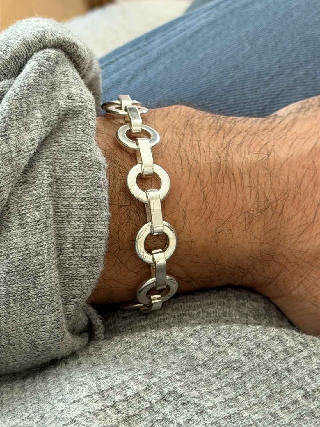 Side view of the sterling round link bracelet on the wrist, light reflecting off the flat faces of each ring and bar