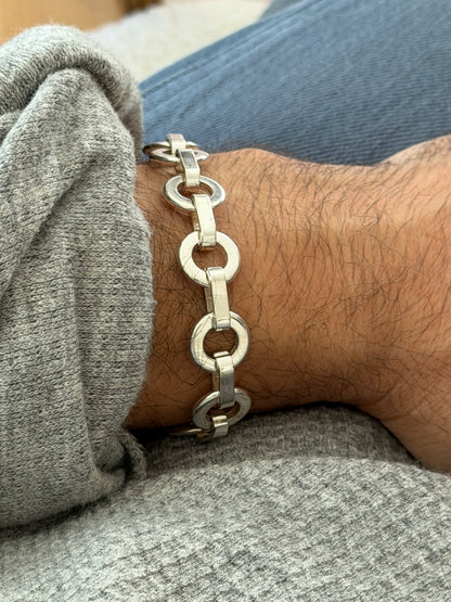 Side view of the sterling round link bracelet on the wrist, light reflecting off the flat faces of each ring and bar
