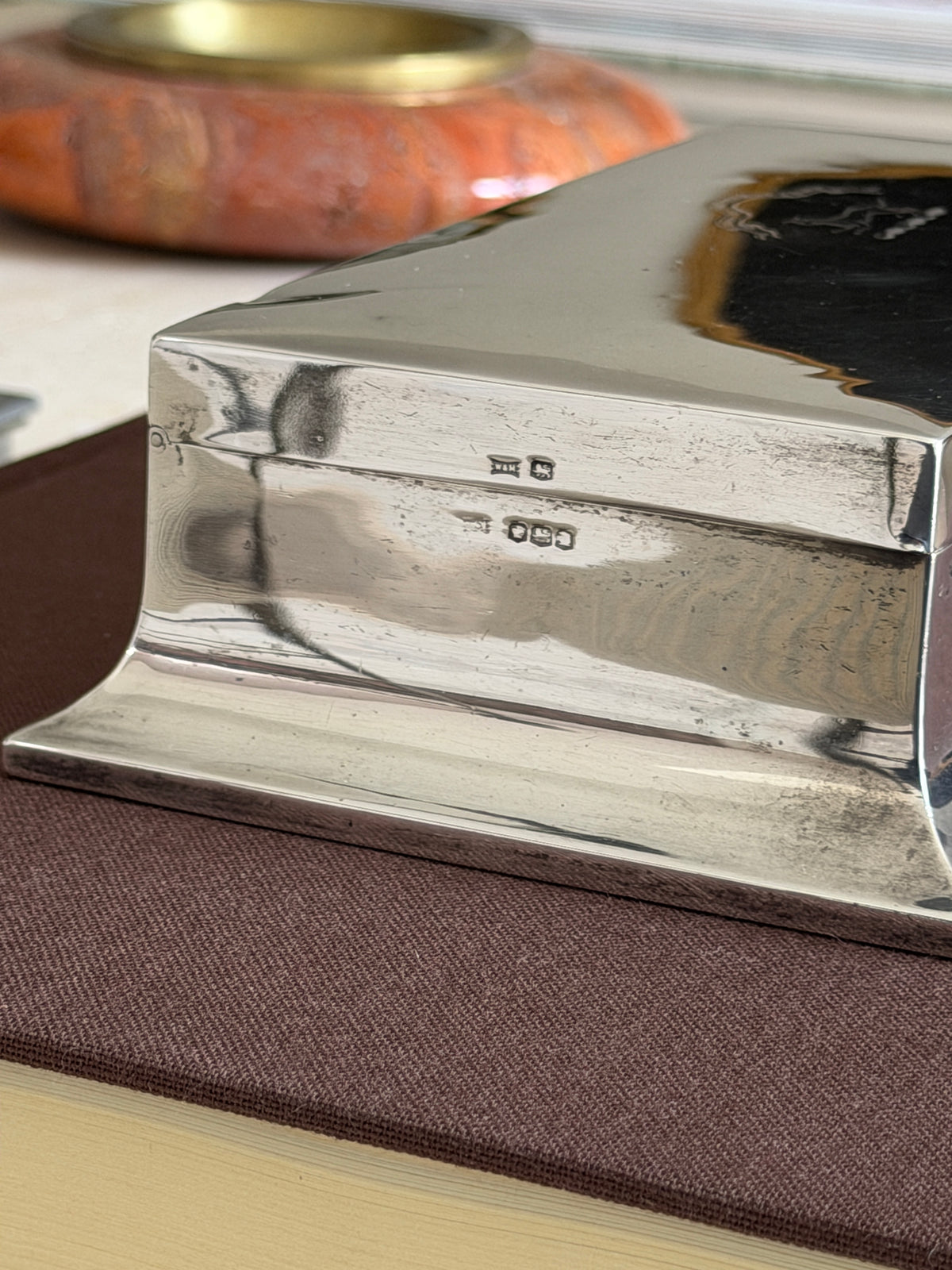 Detail of the Walker and Hall hallmarks on the polished side above the flared base, a red stone ashtray blurred behind