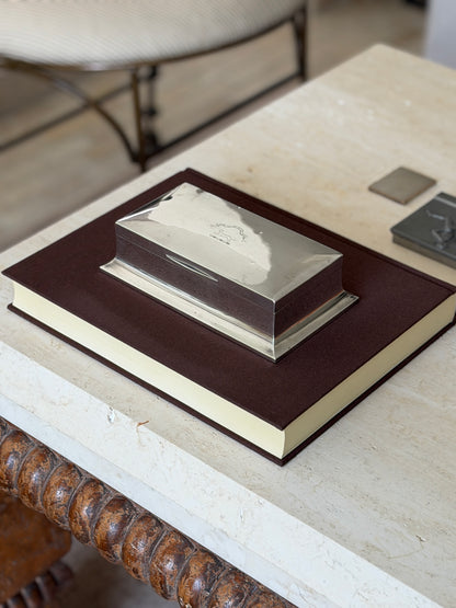 English sterling box on a brown book on a travertine coffee table with a bobbin turned base and pewter boxes nearby
